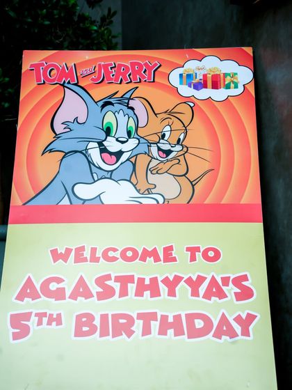 A personalized "Welcome to Agasthya's 5th Birthday" sign featuring Tom and Jerry.