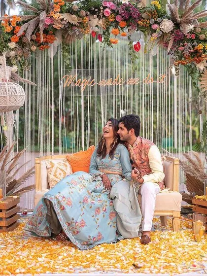 Another joyful moment from their Mehendi celebration. They are sharing a laugh on their beautifully decorated stage, surrounded by flowers and happy vibes.