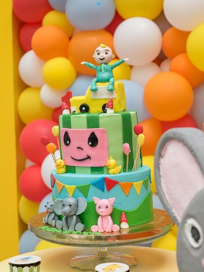A vibrant Cocomelon-themed cake takes center stage. The colorful tiers and character details make it a perfect centerpiece for a first birthday celebration.