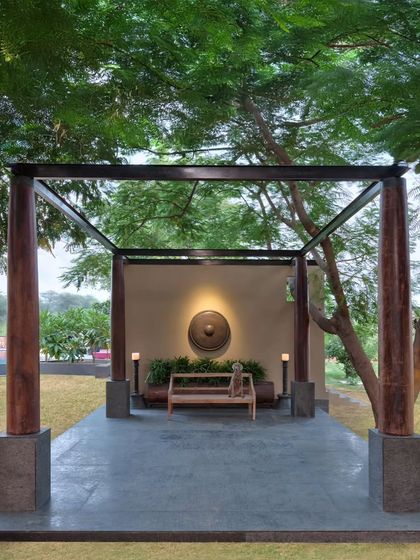 The open-to-sky entrance pavilion at Aishbagh, constructed with old teak wood columns from Kerala. This transitional space serves as a pause point, welcoming guests with a sense of quiet grandeur and a connection to natural elements.