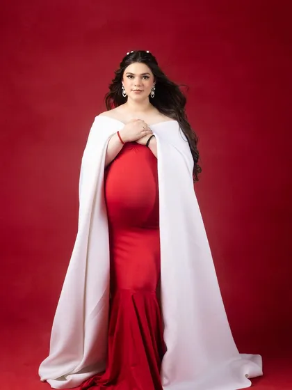 Bold, beautiful, and radiating pure elegance. This portrait, with its striking red dress and white cape, captures motherhood like never before.