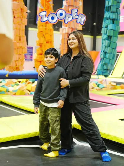 A mother and son pose for a picture in the foam pit area, a perfect backdrop for a family photo.