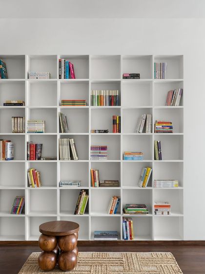 A minimalist, grid-style bookshelf in the West Coast Residence creates a clean and organized display for the client's book collection.