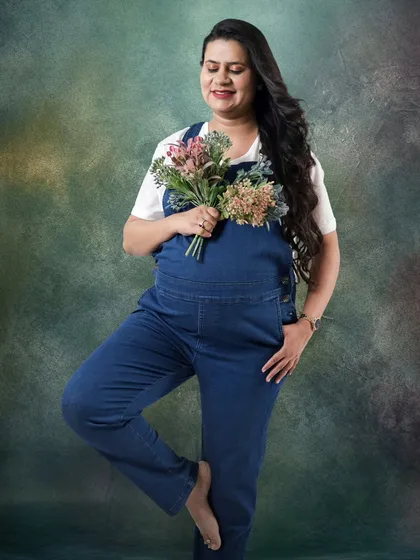 Who says maternity shoots can't be fun and casual? This expecting mother looks so happy and relaxed in denim dungarees, holding a small bouquet.
