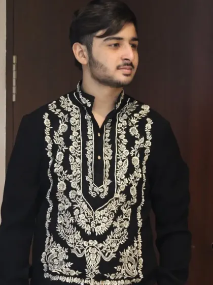 A client wearing a black kurta with intricate gold embroidery, paired with white trousers.