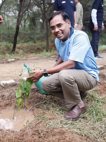 A volunteer from Carrier India happily waters a newly planted Kaala Khinna sapling, a native tree that helps prevent soil erosion in fragile bhood land areas.