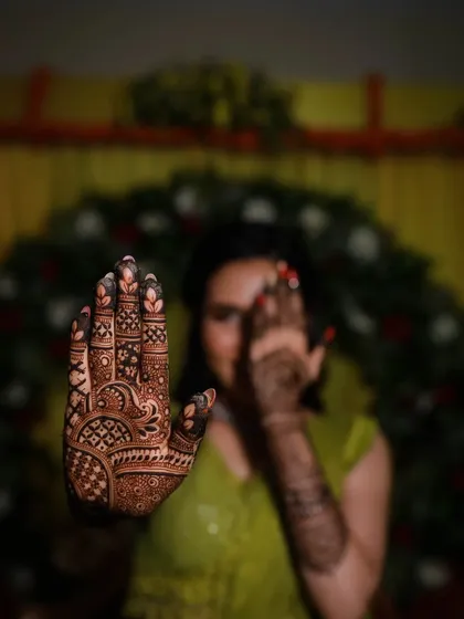 A creative pose focusing on the detailed palm work, with the happy bride smiling in the background.