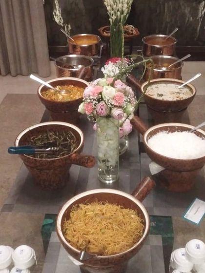 An Asian-themed buffet spread served in rustic, earthy-toned bowls with handles. This setup includes a variety of noodles, rice, and curries, perfect for an oriental food fix.