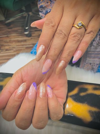 A mix of shimmery golden and lavender nails with an angular French tip design.