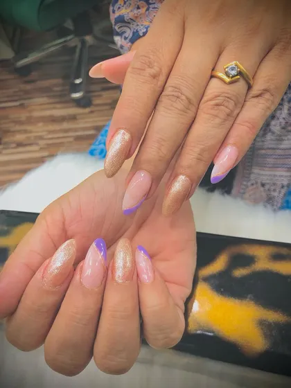 A mix of shimmery golden and lavender nails with an angular French tip design.