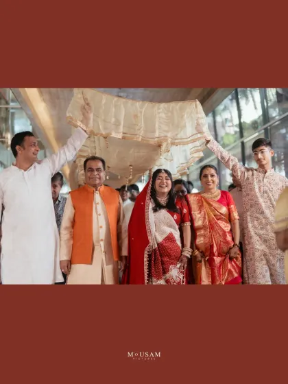 The bride's entry during a Bengali wedding, sheltered by a 'palki' held by her family. Her joyful smile as she is escorted to the mandap is a beautiful, heartwarming moment of family love and support.