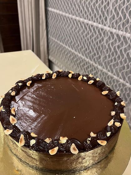 A full view of our Double Chocolate Baked Cheesecake. The glossy ganache and border of toasted hazelnuts promise pure indulgence.