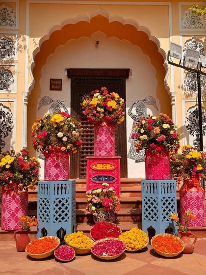 A beautiful floral display at the entrance of a haveli. The colorful flowers in painted vases create a warm and welcoming sight for guests.