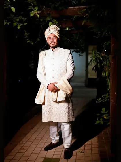 A classic full-length portrait of the groom on his wedding night. His elegant sherwani and calm demeanor make for a timeless and handsome photograph.
