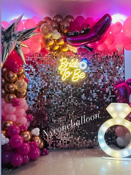 This shot highlights the key elements of the bachelorette party decor: the 'Bride to Be' neon sign, the light-up diamond ring, and the shimmering backdrop.