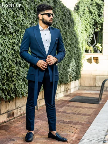 A client models a modern navy blue suit with a unique belted waist and flap pockets. Paired with loafers, it's a perfect example of contemporary power dressing.