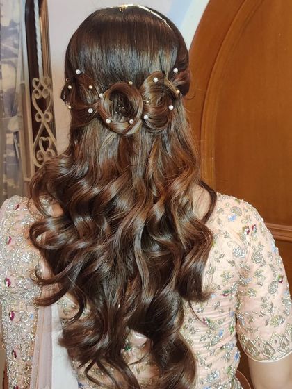 A cute and creative half-up style featuring a bow made of hair, adorned with pearls. A unique look for any special occasion.