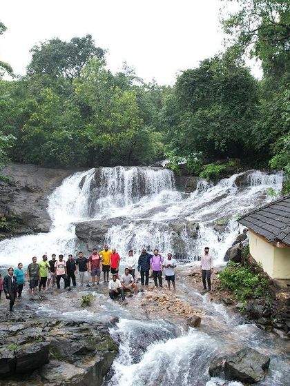 A group photo at a scenic waterfall in Uttara Kannada, with a small temple nearby adding to the serene and spiritual vibe of the place.