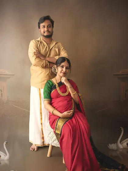 A regal portrait of an expecting couple in traditional attire, posed with painted swans to add a touch of artistic elegance.