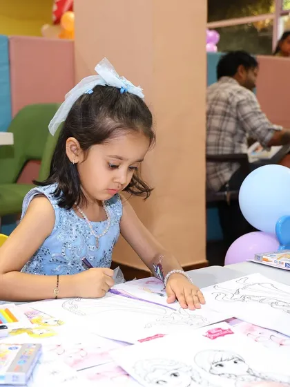 The birthday princess focuses on her coloring sheet at the designated craft table. This is a great way to provide a variety of activities for different interests.