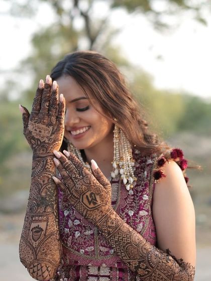 A smile that shows off her stunning mehendi. The intricate henna design is the star, complemented by soft, natural makeup.