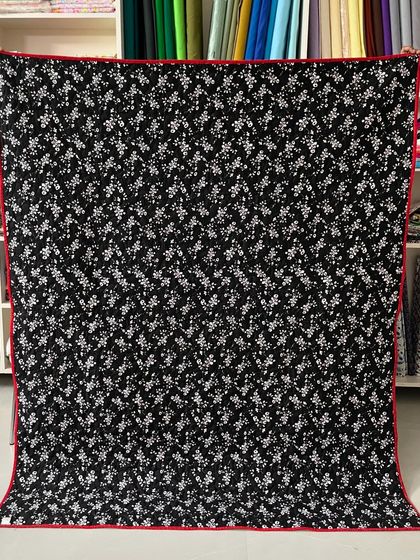 The back of the quilt, featuring a black and white floral print with a red binding.