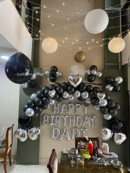 A clear view of the 'Happy Birthday Dad' balloon setup, showing the silver foil letters and heart-shaped accents.