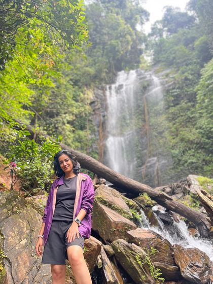 A trekker sits on a rock ledge, enjoying the view of Hidlumane Falls.