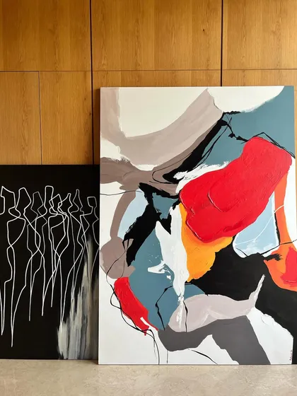 Two of my abstract canvas paintings side-by-side. One is a 'Colour Cluster' with bold, energetic shapes, while the other is a monochrome piece of continuous-line figures, showing the duality in my abstract style.