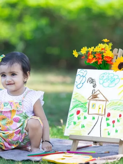 A happy smile for her first birthday. This creative setup with a hand-drawn picture on an easel adds a personal and artistic touch to her milestone celebration photos.