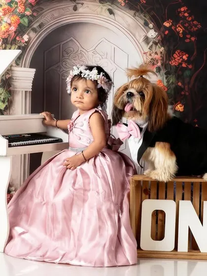 A charming photo of the birthday girl and her dog posing obstáculos by the mini piano.