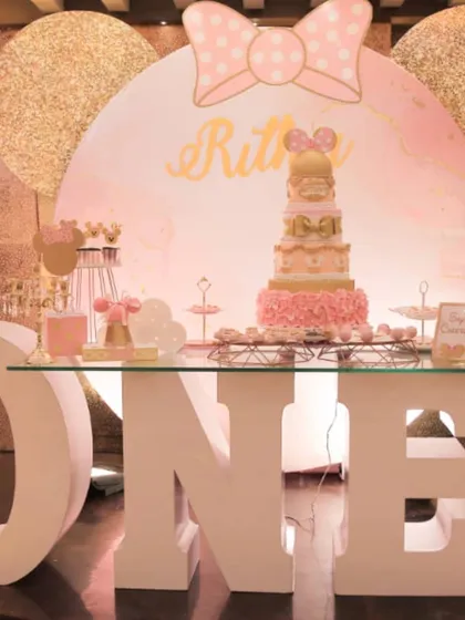 A chic Minnie Mouse first birthday setup. The large light-up "ONE" marquee letters and a rose gold color scheme give this classic theme a modern and glamorous touch.