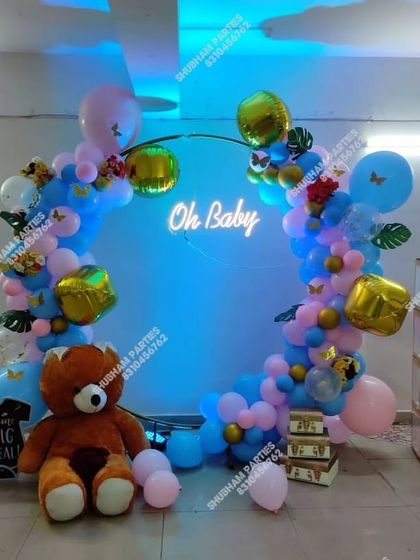 A teddy bear themed "Oh Baby" decoration with a circular balloon frame and blue lighting.