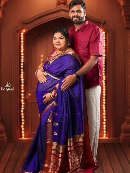A lovely couple's portrait in traditional attire, standing before an ornate doorway setup with festive lights.