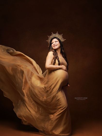 A beautiful solo portrait in a golden gown with a sunburst crown. The flowing fabric and upward gaze create a hopeful and angelic image.