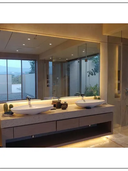 Functionality for two is key in this master bathroom design. It features dual vessel sinks on a floating vanity and a large, backlit mirror that provides ample, even lighting, all while overlooking a beautiful view.