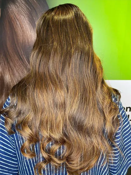 The final result of a caramel brunette balayage, styled with soft curls to enhance the color.