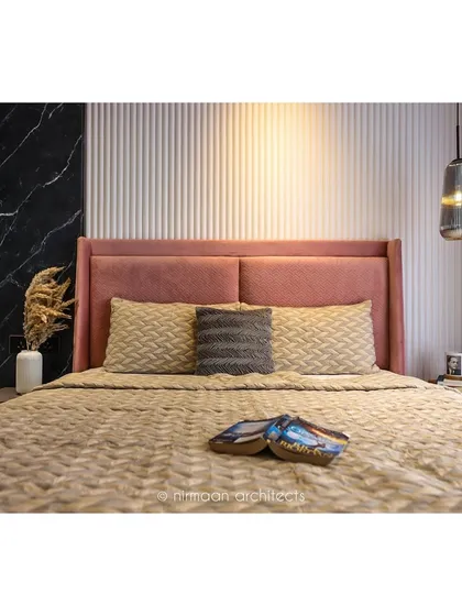 A close-up of the bed in the 'Atmosphere' master bedroom. The combination of the pink headboard, textured bedding, and dramatic accent wall creates a bold yet sophisticated look.