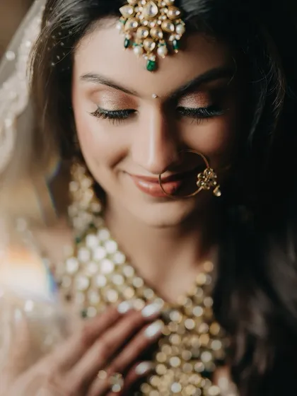 An intimate close-up of bride Raashi. Her serene expression and the beautiful details of her makeup and jewelry are the focus of this soft and emotional portrait.