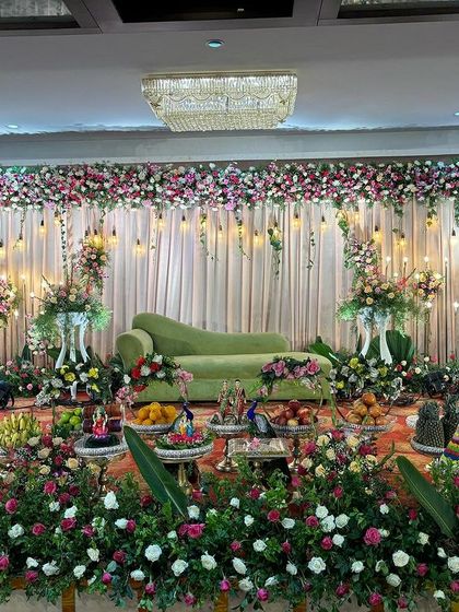 A full view of the elegant stage with the green sofa and floral arrangements.