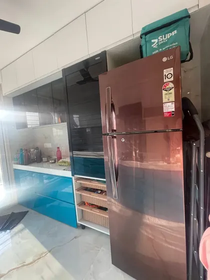 This view shows the integration of appliances, with dedicated space for the refrigerator and a built-in unit for the oven, creating a clean, uncluttered look.