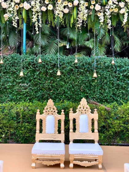 The ornate thrones for the bride and groom, set against a backdrop of hanging floral strings and temple bells.
