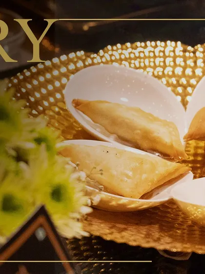 Crispy, golden appetizers served in an elegant, shell-shaped dish on a textured gold platter. Our presentation ensures every bite feels special.