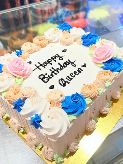 A beautiful square cake for a "Queen," decorated with a rainbow of buttercream roses.