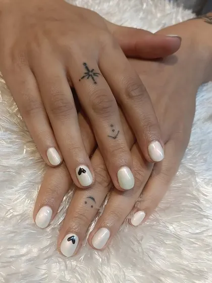 A minimalist yet chic design featuring pearly white nails with tiny, hand-painted black hearts. This look is perfect for those who appreciate subtle details and a clean aesthetic.