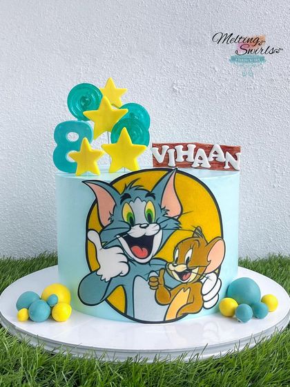 The classic chase continues on this Tom and Jerry themed cake. We used an edible print to capture the iconic duo, surrounded by fun, handmade fondant stars and lollipops for a playful birthday cake.