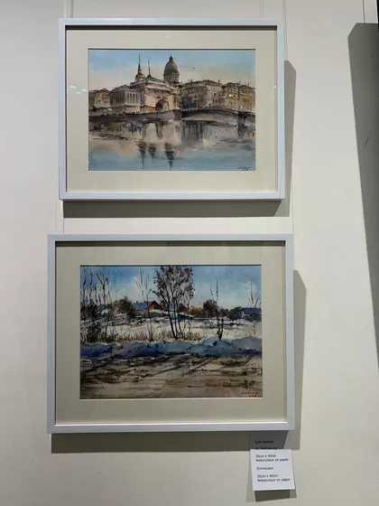 A closer look at my framed watercolor paintings on display at the gallery. One is a cityscape and the other is a winter landscape.