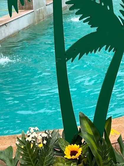 A close-up of a palm tree cutout prop placed by the edge of the pool, adding to the beach party atmosphere.