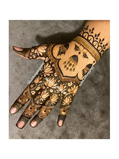 A stylish design for the back of the hand. This piece features hanging jhumka (earring) motifs and a cuff of lotus flowers, making it a very popular choice for guests at a wedding.