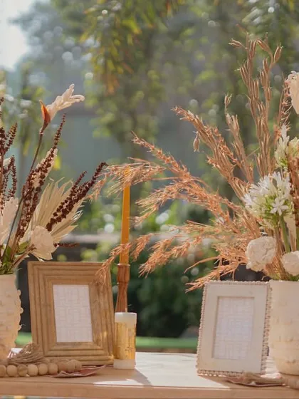 Tabletop decor featuring dried flowers, pampas grass, and empty photo frames, creating a personalized and bohemian vibe for the Haldi celebration.